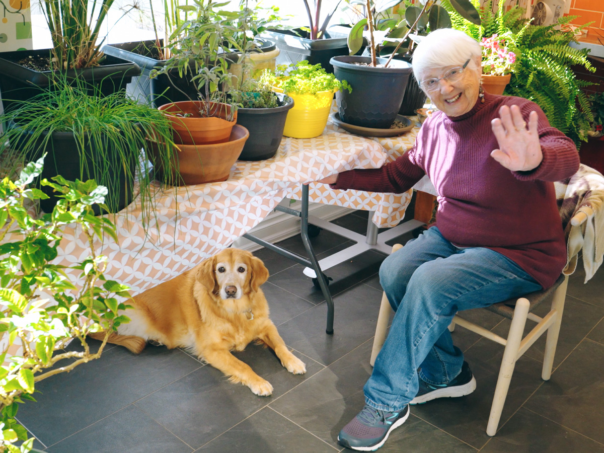 Resident enjoying time in the garden centre surrounded by potted plants and natural light.