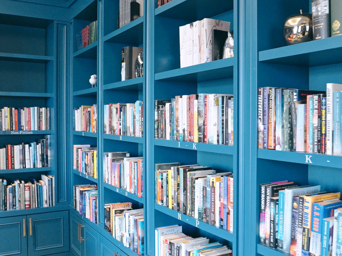 Blue built-in bookshelves filled with books in a cozy library space.