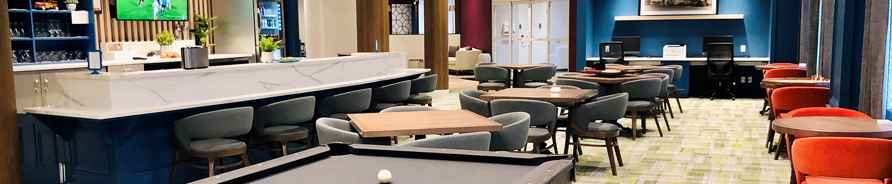Contemporary lounge and bar area with comfortable seating, tables, and a warm, inviting design.