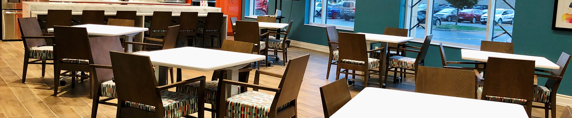 Spacious dining area with neatly arranged tables and chairs, warm finishes, and large windows overlooking the terrace.