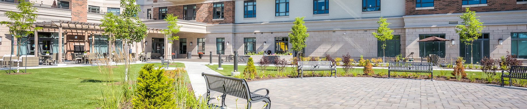 Kingsbridge retirement residence exterior with landscaped courtyard, walkways, and elegant building facade.