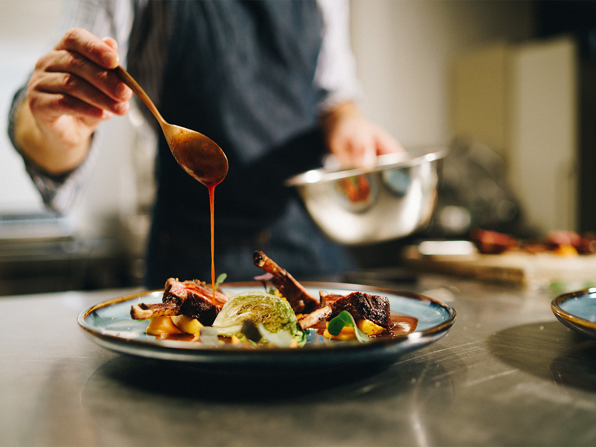 Chef plating a gourmet meal in a professional kitchen with care and attention to detail.